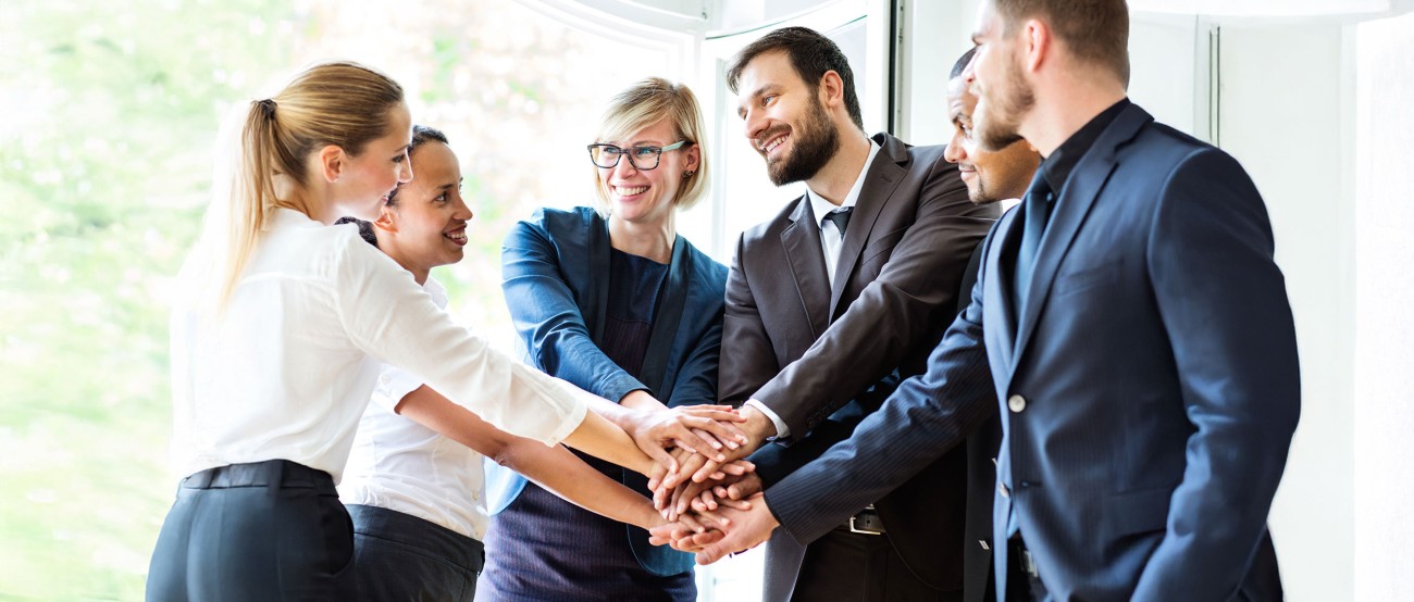Ein Vertrieb und Marketing Team von 6 Personen die die Hände aufeinander legen